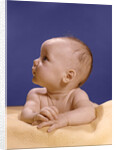 1960s portrait of baby on yellow blanket resting on folded arms head turned to right looking up by Anonymous