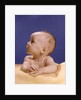 1960s portrait of baby on yellow blanket resting on folded arms head turned to right looking up by Anonymous