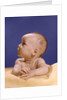1960s portrait of baby on yellow blanket resting on folded arms head turned to right looking up by Anonymous