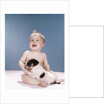 1960s smiling baby girl sitting in diapers playing with young black and white puppy dog by Anonymous