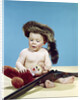 1960s baby boy wearing coonskin cap with stuffed animal and shotgun by Anonymous