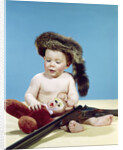 1960s baby boy wearing coonskin cap with stuffed animal and shotgun by Anonymous
