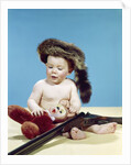 1960s baby boy wearing coonskin cap with stuffed animal and shotgun by Anonymous