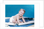 1960s baby eyes closed funny facial expression crawling on rolling out blueprints by Anonymous