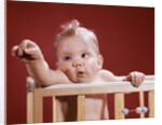 1960s baby reaching out from crib by Anonymous