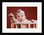 1960s baby reaching out from crib by Anonymous