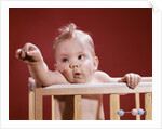 1960s baby reaching out from crib by Anonymous