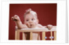 1960s baby reaching out from crib by Anonymous