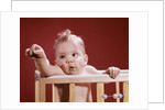1960s baby reaching out from crib by Anonymous
