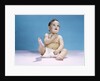 1960s baby wearing diaper sitting looking up and kicking one leg up by Anonymous