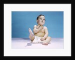1960s baby wearing diaper sitting looking up and kicking one leg up by Anonymous