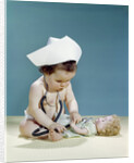 1960s baby wearing nurse nurse's cap stethoscope listening to doll heartbeat chest by Anonymous