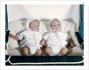 1950s 1960s twin boys dressed in white lying in stroller side by side by Anonymous