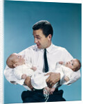 1960s father holding twin babies infants looking down at one of them by Anonymous