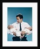1960s father holding twin babies infants looking down at one of them by Anonymous