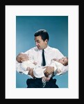 1960s father holding twin babies infants looking down at one of them by Anonymous