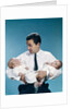 1960s father holding twin babies infants looking down at one of them by Anonymous