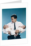 1960s father holding twin babies infants looking down at one of them by Anonymous