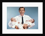 1960s smiling man father looking at camera holding twin babies infants by Anonymous
