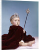 1960s baby girl wearing rhinestone tiara and red velvet cloak holding scepter by Anonymous