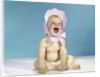 1960s baby wearing pink checked bonnet laughing by Anonymous