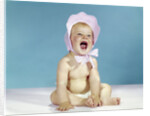 1960s baby wearing pink checked bonnet laughing by Anonymous