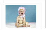 1960s baby wearing pink checked bonnet laughing by Anonymous