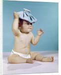 1960s baby sitting with ice pack on top of head by Anonymous