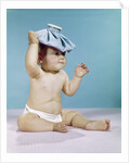 1960s baby sitting with ice pack on top of head by Anonymous