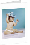 1960s baby sitting with ice pack on top of head by Anonymous