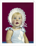 1960s blonde baby blue eyes wearing ruffled bonnet facial expression of wonder looking at camera by Anonymous