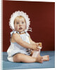 1960s baby girl ruffled bonnet holding bottle funny facial expression looking at camera by Anonymous