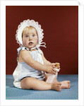 1960s baby girl ruffled bonnet holding bottle funny facial expression looking at camera by Anonymous