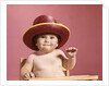 1960s baby making face wearing red straw hat by Anonymous