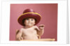 1960s baby making face wearing red straw hat by Anonymous