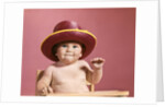1960s baby making face wearing red straw hat by Anonymous