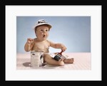 1960s baby with funny facial expression wearing painters cap holding paintbrush sitting by paint can by Anonymous