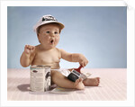 1960s baby with funny facial expression wearing painters cap holding paintbrush sitting by paint can by Anonymous