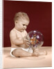 1960s baby sitting holding clear plastic toy ball with butterflies inside by Anonymous