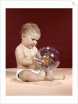 1960s baby sitting holding clear plastic toy ball with butterflies inside by Anonymous