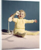 1960s baby holding telephone head set by Anonymous