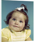 1960s brunette baby girl round chubby face yellow dress ribbon topknot interested sincere facial expression looking at camera by Anonymous