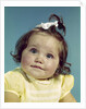 1960s brunette baby girl round chubby face yellow dress ribbon topknot interested sincere facial expression looking at camera by Anonymous