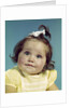 1960s brunette baby girl round chubby face yellow dress ribbon topknot interested sincere facial expression looking at camera by Anonymous