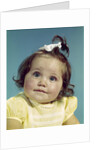 1960s brunette baby girl round chubby face yellow dress ribbon topknot interested sincere facial expression looking at camera by Anonymous