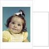 1960s brunette baby girl round chubby face yellow dress ribbon topknot interested sincere facial expression looking at camera by Anonymous