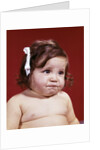1960s portrait of chubby unhappy baby girl with white ribbon bow in messy hair by Anonymous