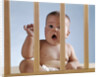 1960s baby in crib or playpen looking through bars alarmed expression by Anonymous