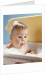 1960s baby with a surprised facial expression in bathtub covered with soap bubbles by Anonymous