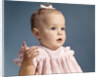 1960s baby girl wearing pink dress with a bow in her hair pointing a finger by Anonymous